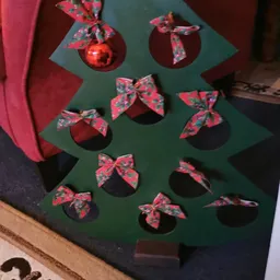 Groene kerstboom van karton versierd met rode kerstballen en rode strikjes als decoratie