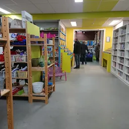 Winkelinterieur met houten stellingen, boekenrekken langs de muur en kleurrijke gele wanden