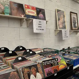 Uitstalling van tweedehands vinyl records, cd's en dvd's op tafels en in rekken met prijskaartjes