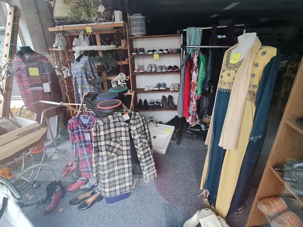 Winkelinterieur met kledingrekken, schoenenstellage en diverse tweedehands kleding uitgestald