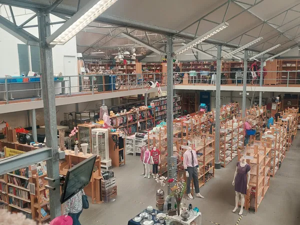 Overzicht van de winkelvloer met meerdere verdiepingen en veel stellingen vol met spullen in een kringloopwinkel