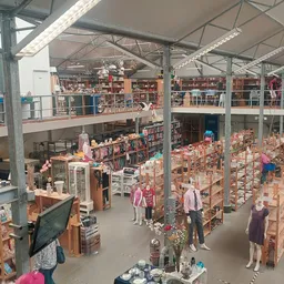 Overzicht van de winkelvloer met meerdere verdiepingen en veel stellingen vol met spullen in een kringloopwinkel