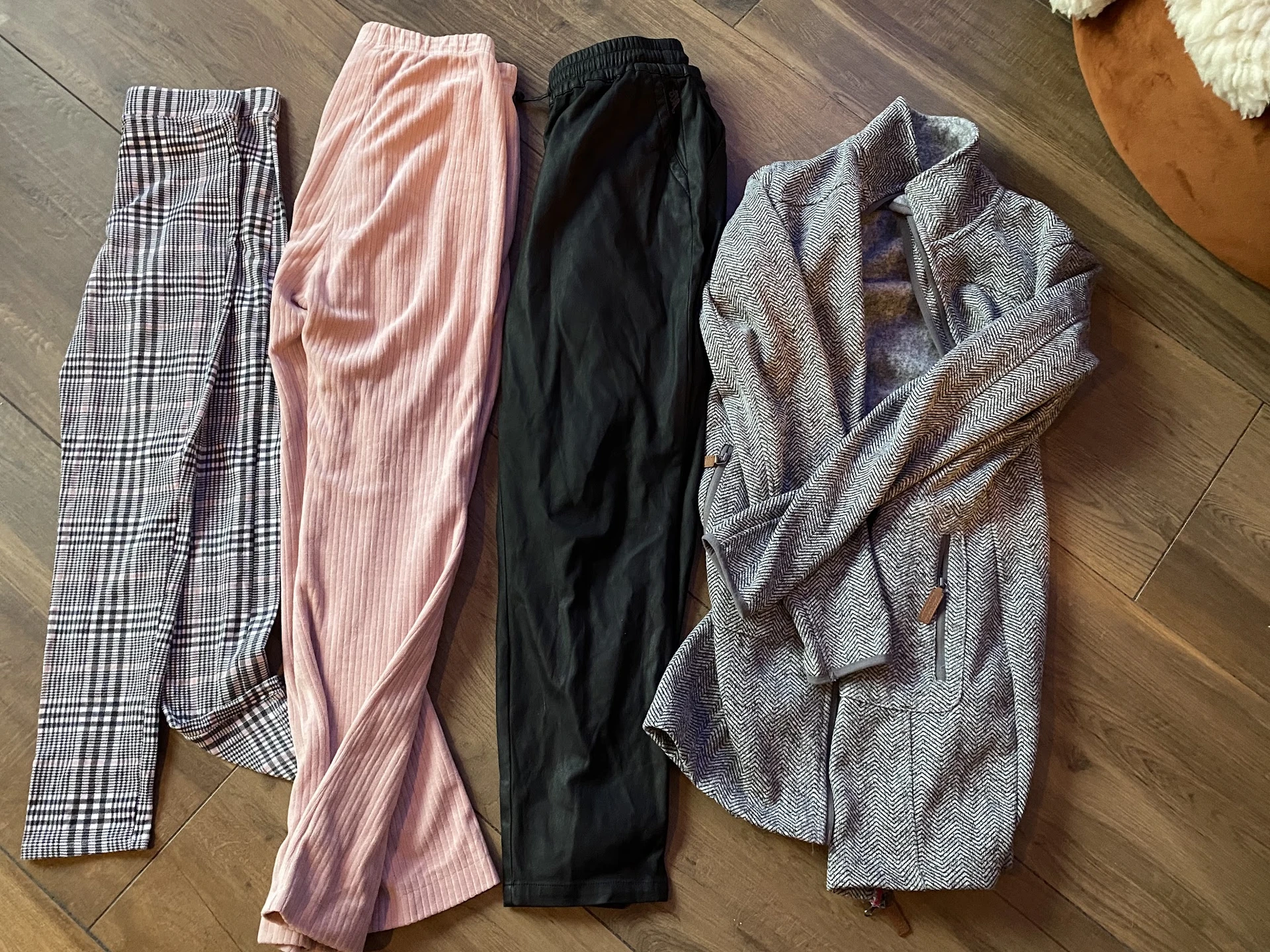 Vier opgestelde broeken en pantalons in verschillende kleuren en patronen op houten vloer