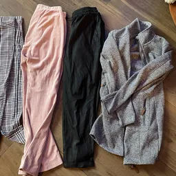 Vier opgestelde broeken en pantalons in verschillende kleuren en patronen op houten vloer