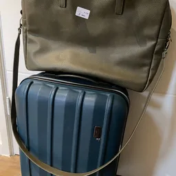 Tweedehands bagageset: groene schoudertas en blauwe koffer met ribbelpatroon.