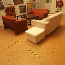 Tweedehands zitmeubels in diverse kleuren opgesteld in de winkel, met oranje stoelen en een crèmekleurige fauteuil met voeten