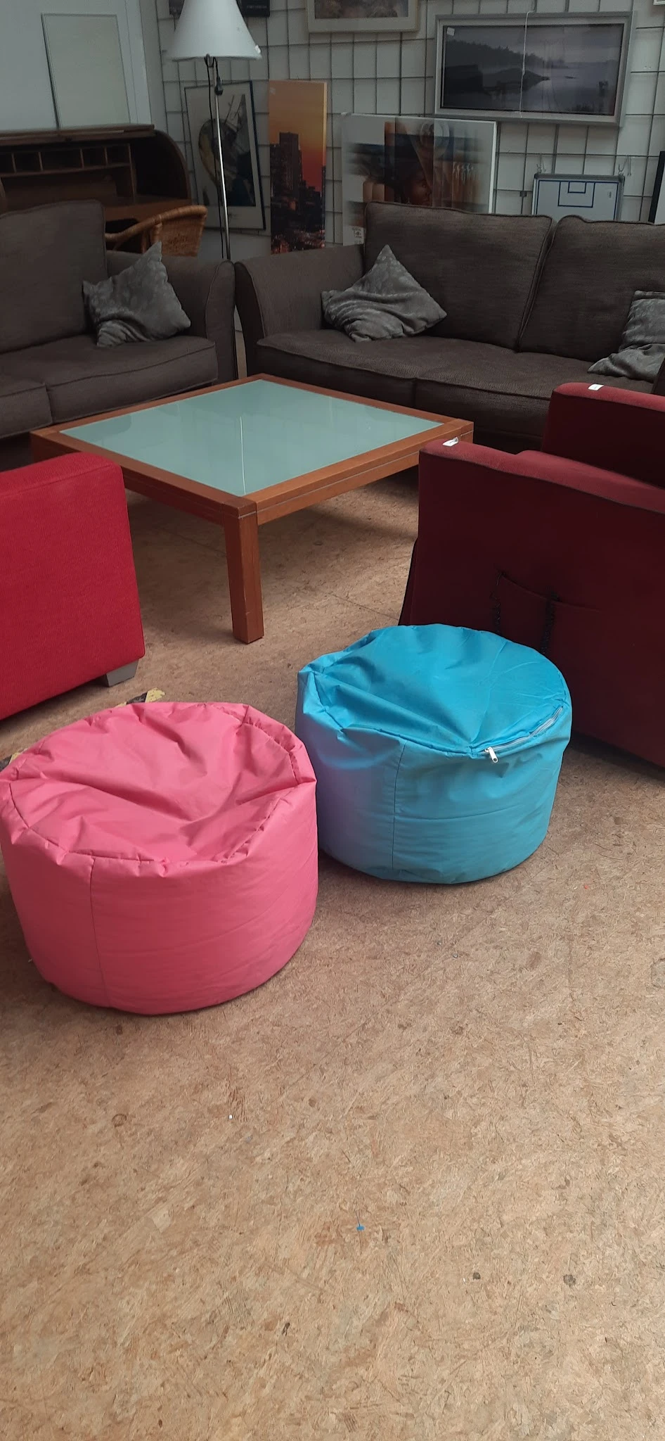 Twee grote poefen in roze en blauw op betonnen vloer in de winkel