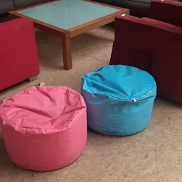 Twee grote poefen in roze en blauw op betonnen vloer in de winkel