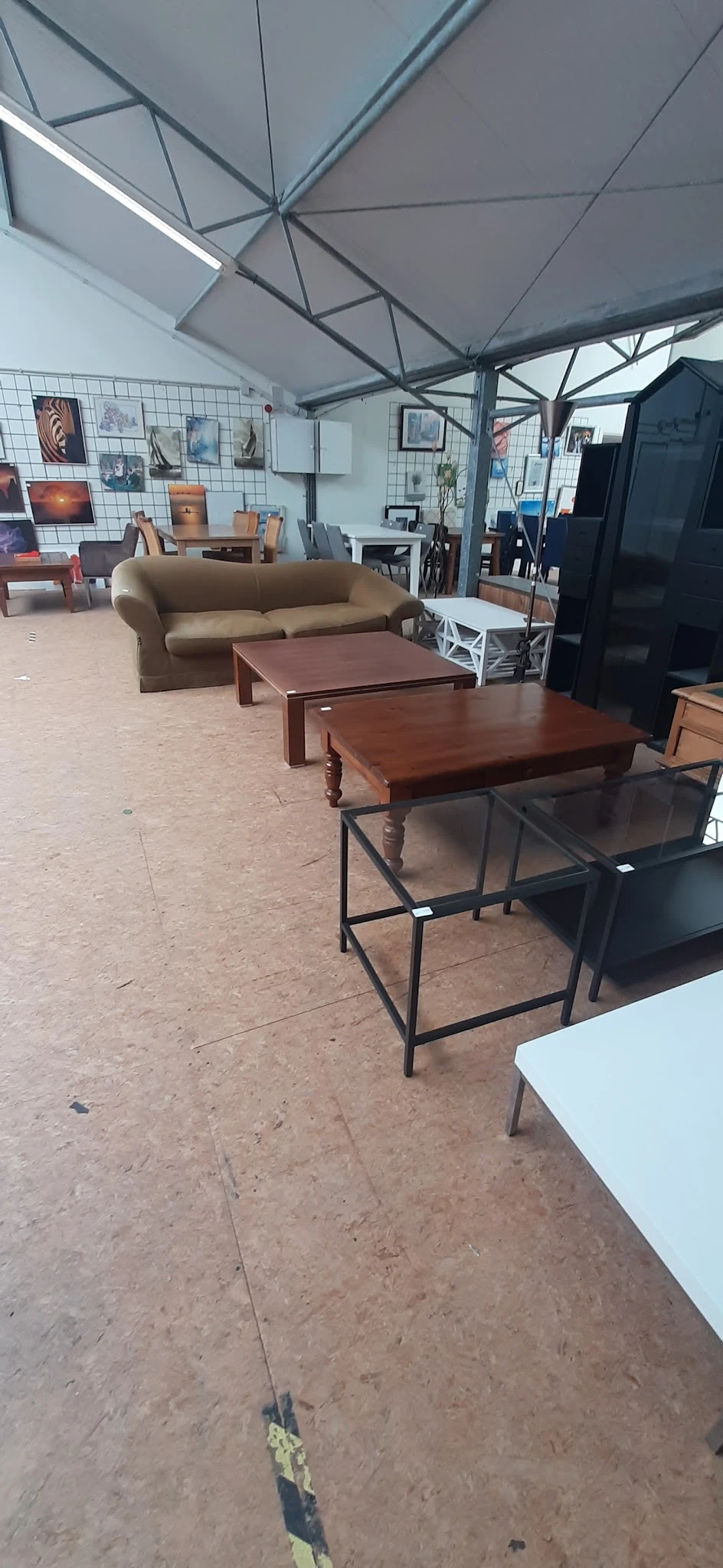 Verschillende houten tafels en een beige bank uitgestald op de winkelvloer