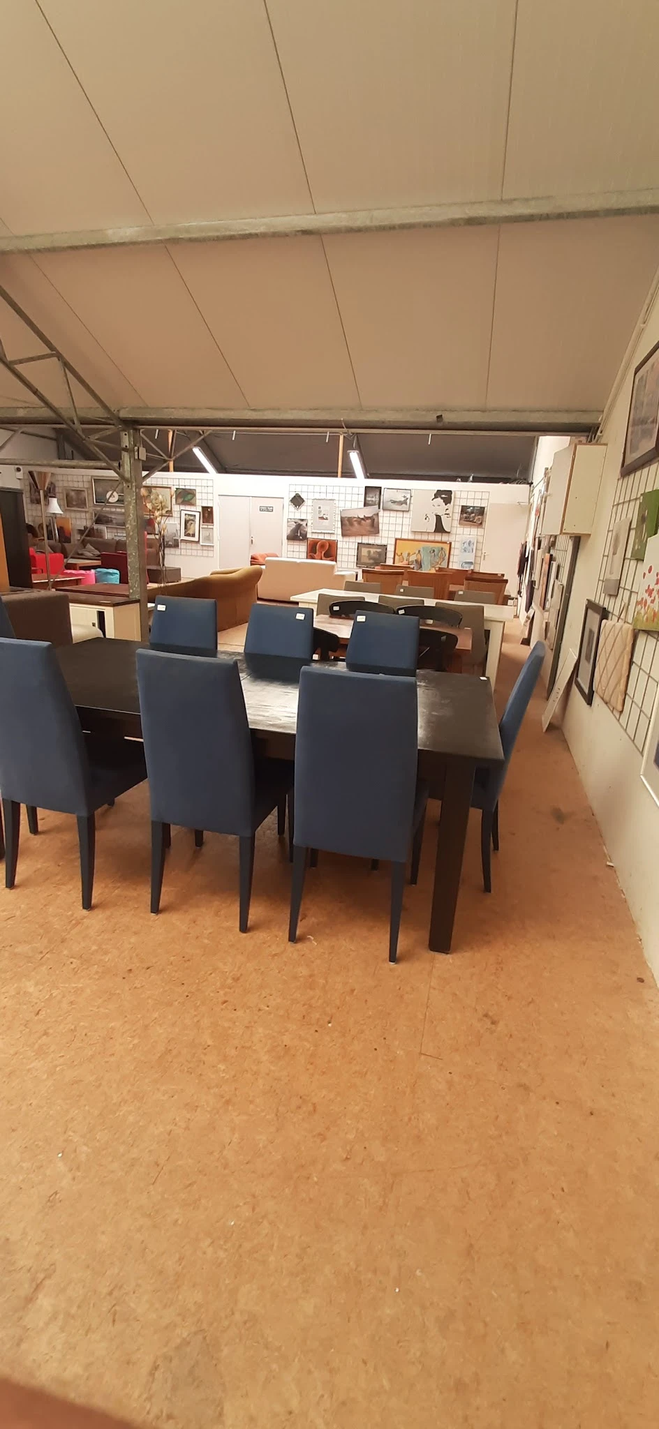 Moderne eettafel met zes blauwe stoelen in een kringloopwinkel
