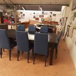 Moderne eettafel met zes blauwe stoelen in een kringloopwinkel