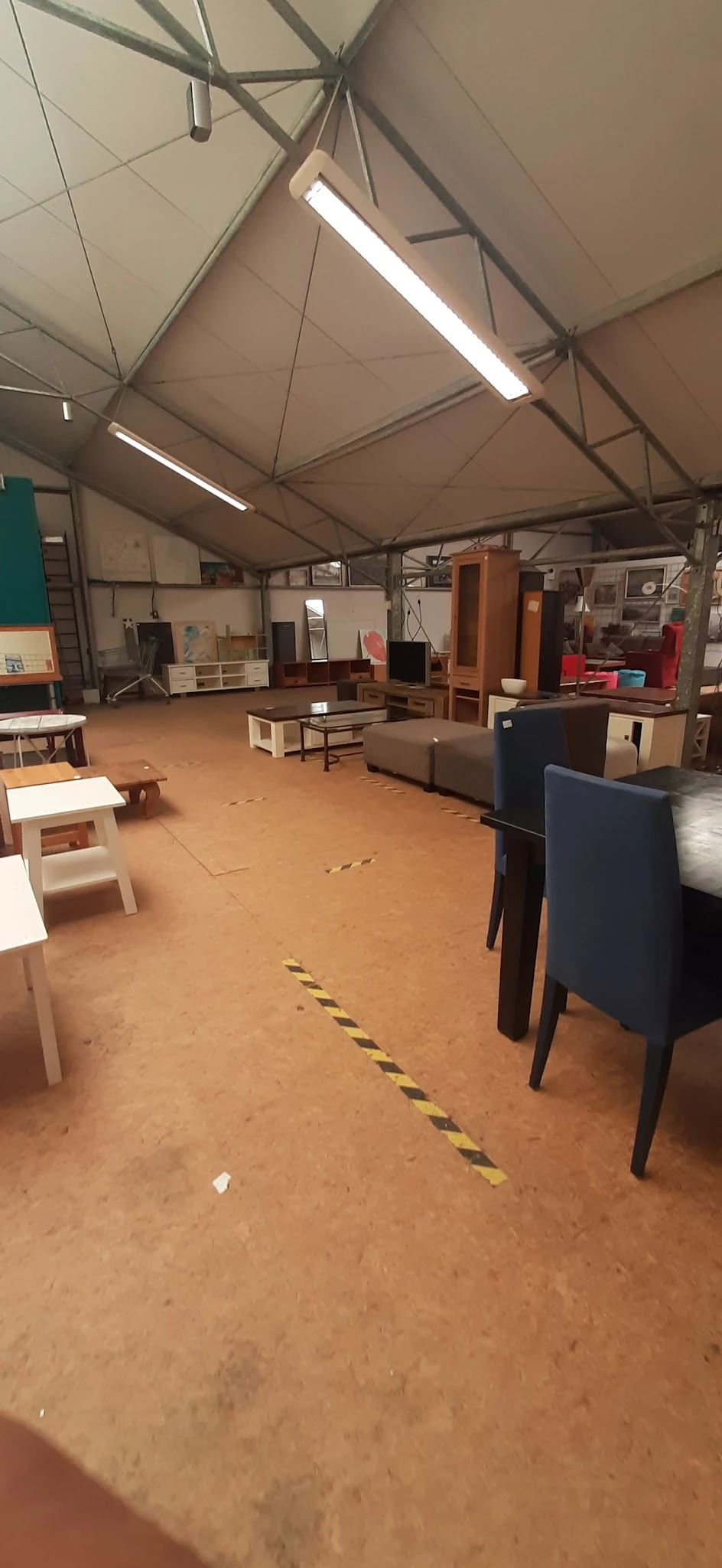 Binnenkant van kringloopwinkel met meubels, kasten en bankstellen verspreid over de vloer