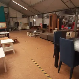 Binnenkant van kringloopwinkel met meubels, kasten en bankstellen verspreid over de vloer