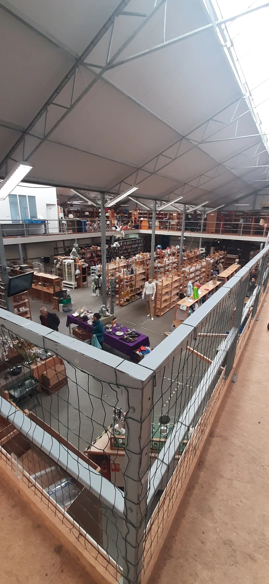 Overzicht van de winkelvloer met kartonnen dozen en stellingen, bezoekers winkelen tussen het aanbod