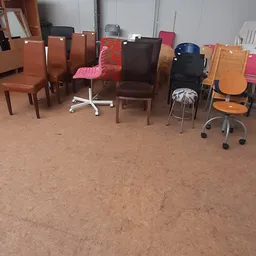 Diverse stoelen en zitmeubelen op de winkelvloer, waaronder bruine stoelen, een roze stoel en baarkrukken