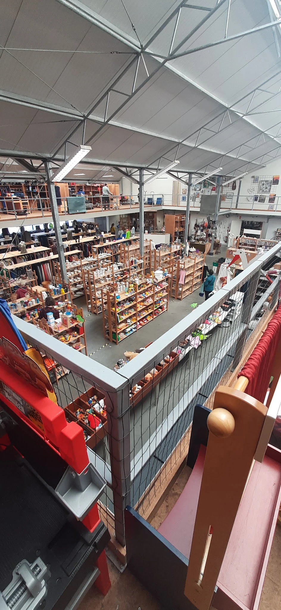 Overzicht van de winkelzaal met houten stellingen vol spullen, vanaf een verhoging gefotografeerd.