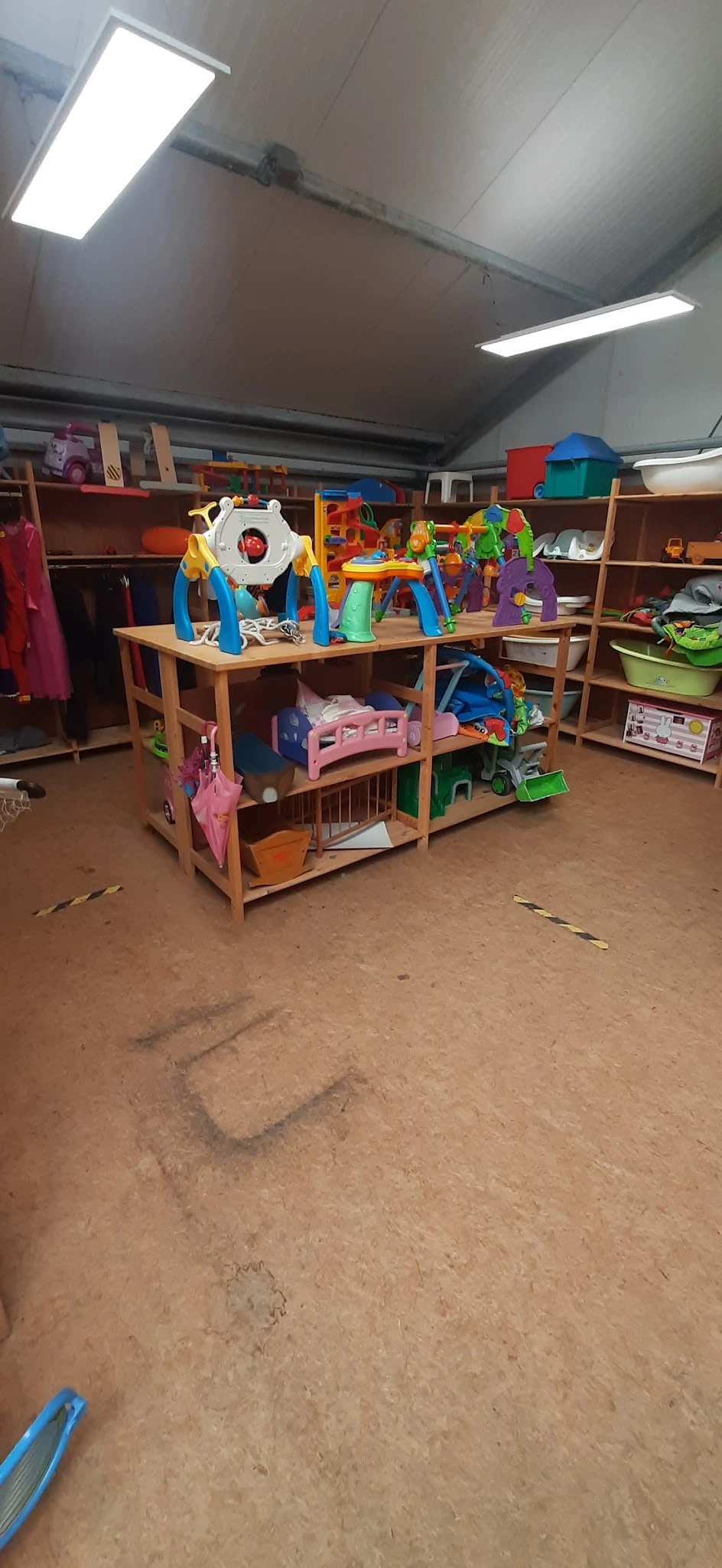 Houten speelhuisje met gekleurde speelgoed en accessoires op kringloopwinkel vloer