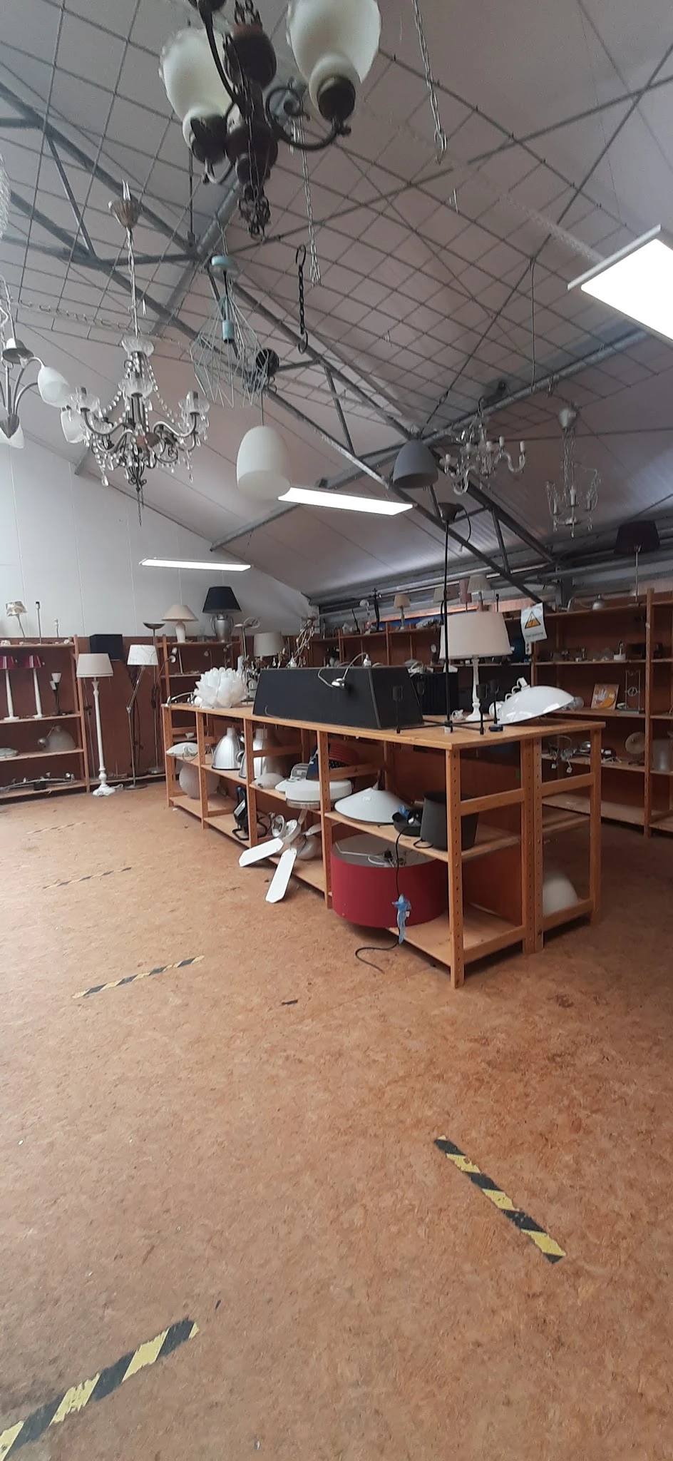 Winkelvloer met houten stellingen, tafels met witte decoratieve items en lampen, fluorescente verlichting aan het plafond