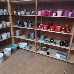 Houten stellingen met uitgestalde huishoudartikelen: kleurrijke potten, bakjes en containers in diverse kleuren
