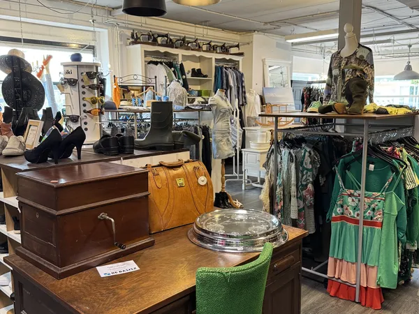 Winkelvloer met houten meubels, kledinrekken en diversen spullen in kringloopwinkel