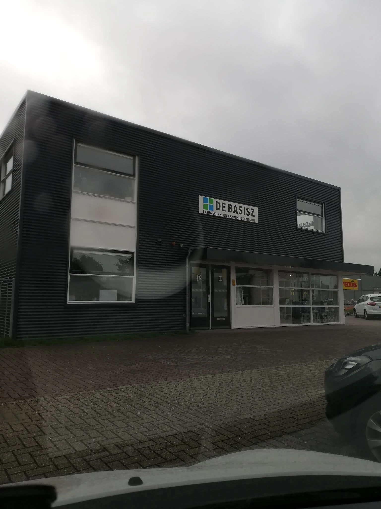 Moderne gevel van kringloopwinkel De Basisz met grote ramen en zwarte gevelbekleding