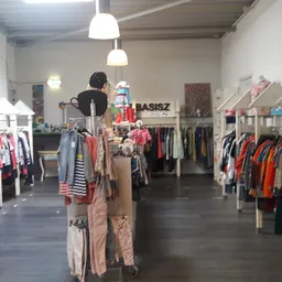 Winkelvloer met rekken vol tweedehands kleding, hangende lampen en een mannequin in het centrum