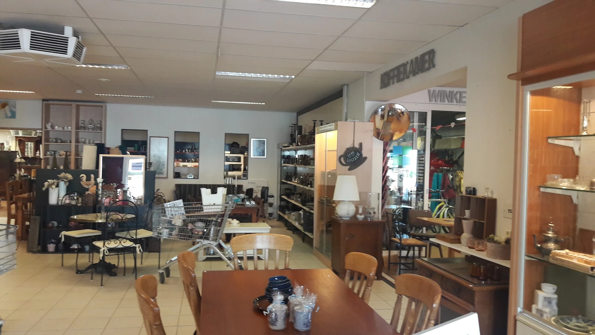 Winkelvloer van kringloopwinkel met tafels, stoelen, stellingen en diverse meubels en spullen.
