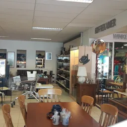 Winkelvloer van kringloopwinkel met tafels, stoelen, stellingen en diverse meubels en spullen.