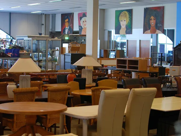 Winkelvloer met houten meubels, tafels, stoelen en lampen in een kringloopwinkel