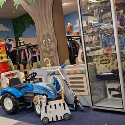 Kindervoertuigen en speelgoed in een kringloopwinkel, waaronder een blauwe driewieler en kinderspeelgoed
