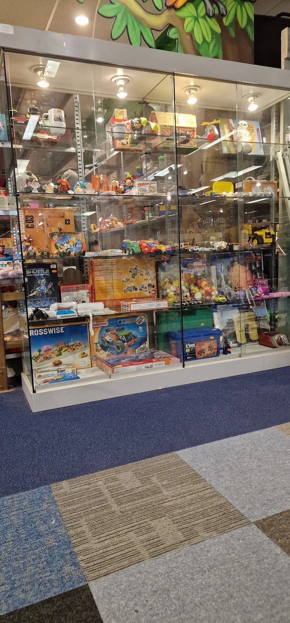 Vitrinekast met tentoongestelde speelgoed, bouwsets en action figures in een kringloopwinkel
