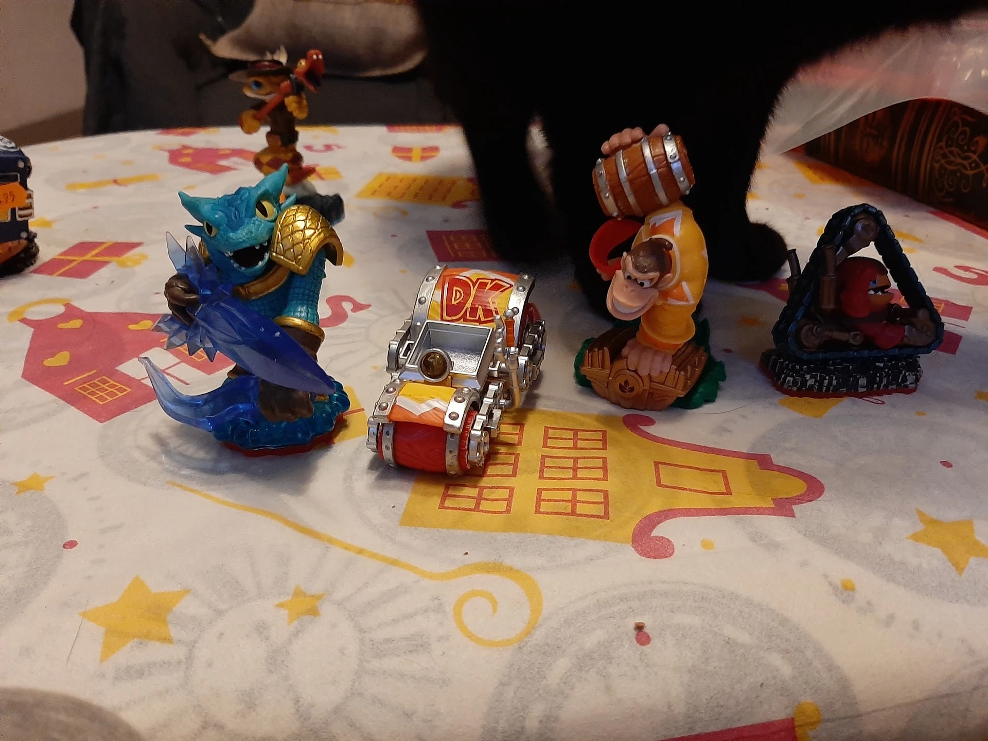 Speelgoedactiefiguren en voertuigen uitgestald op een wit tafelkleed met gekleurde prints