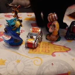 Speelgoedactiefiguren en voertuigen uitgestald op een wit tafelkleed met gekleurde prints