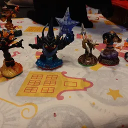 Verzameling speelgoedactiefiguren op een wit kleed met gele sterren en huismotief