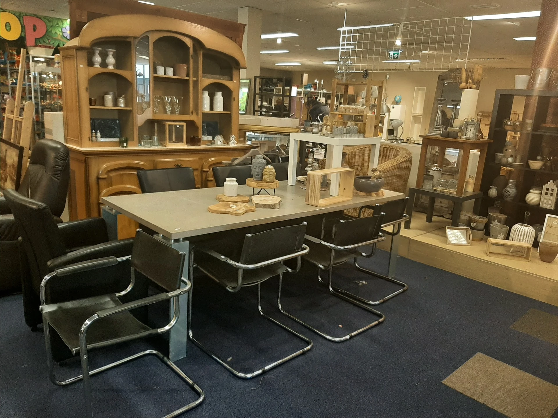 Winkelvloer met tafel, stoelen en houten kasten met decoratieve items