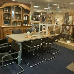 Winkelvloer met tafel, stoelen en houten kasten met decoratieve items