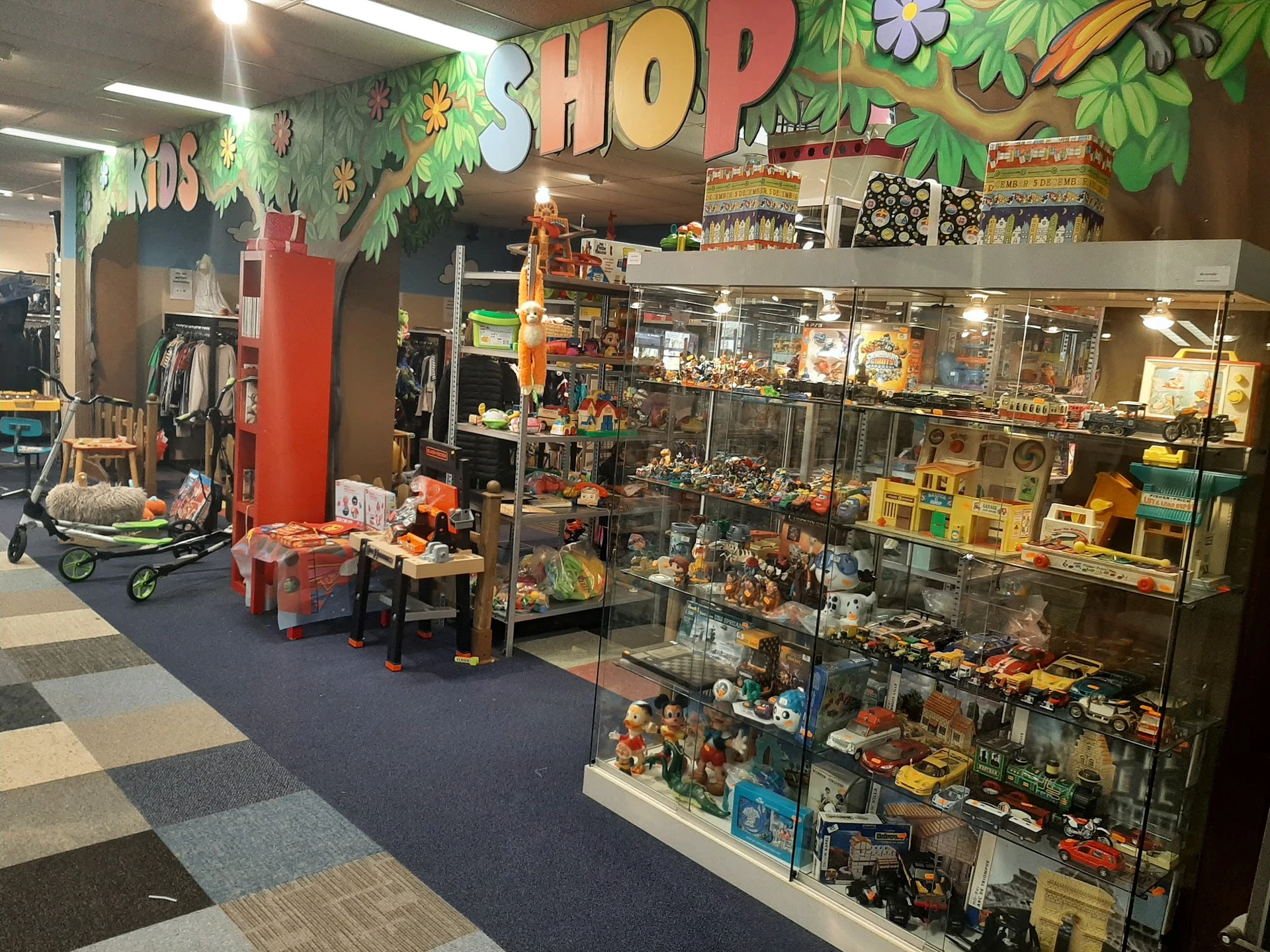 Winkelinterieur met speelgoed en actiefiguren in vitrinekasten, decoratief groen aan plafond met 'HOP'-opschrift
