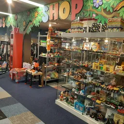 Winkelinterieur met speelgoed en actiefiguren in vitrinekasten, decoratief groen aan plafond met 'HOP'-opschrift