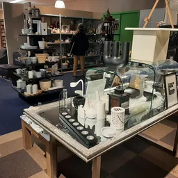 Overzicht van de winkelvloer met toonbanken, schappen en diverse tweedehands artikelen in de kringloopwinkel