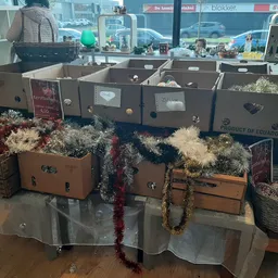 Uitstalling van decoratieve items: koffers versierd met kunstbloemen en slingers op een tafel in de winkel