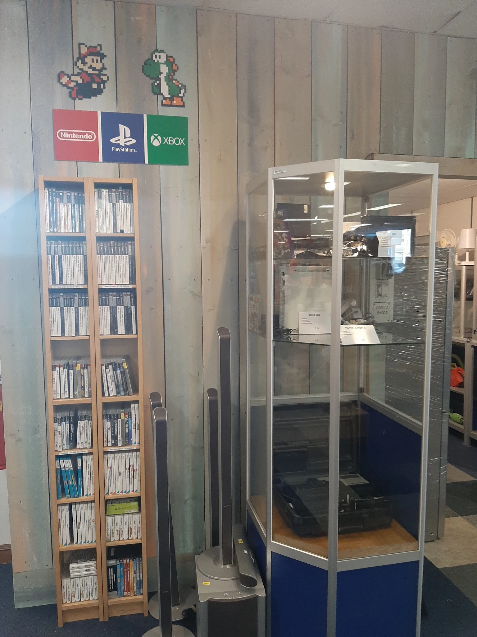 Kast met dvd's en cd's naast vitrinekast met elektronica in kringloopwinkel