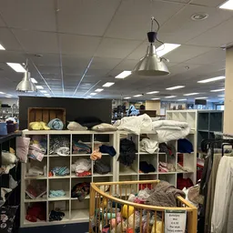 Overzicht van de winkelruimte met stellingen vol huishoudtextiel, beddengoed en diverse kringloopgoederen