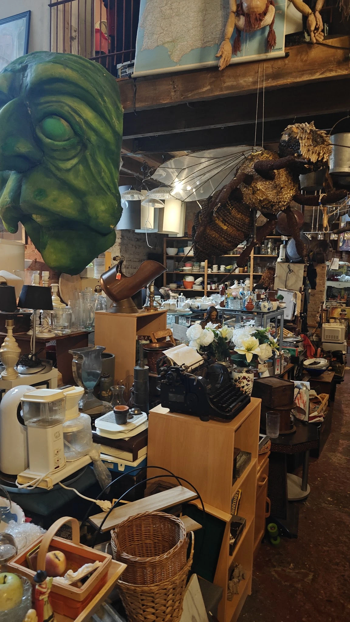 Tweedehands huishoudelijke artikelen en decoratiestukken op stellingen in een kringloopwinkel
