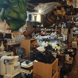 Tweedehands huishoudelijke artikelen en decoratiestukken op stellingen in een kringloopwinkel