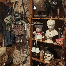 Stellingkast met diverse tweedehandsartikelen: poppen, bustes, servies en decoratieve items