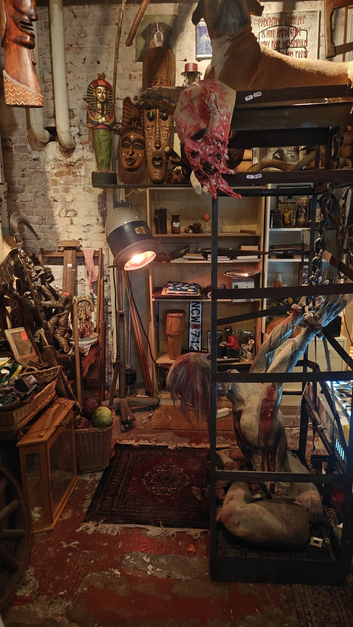 Binnenaanzicht van kringloopwinkel met stellingen vol spullen, vintage lamp, decoratieve objecten en diverse tweedehandsartik