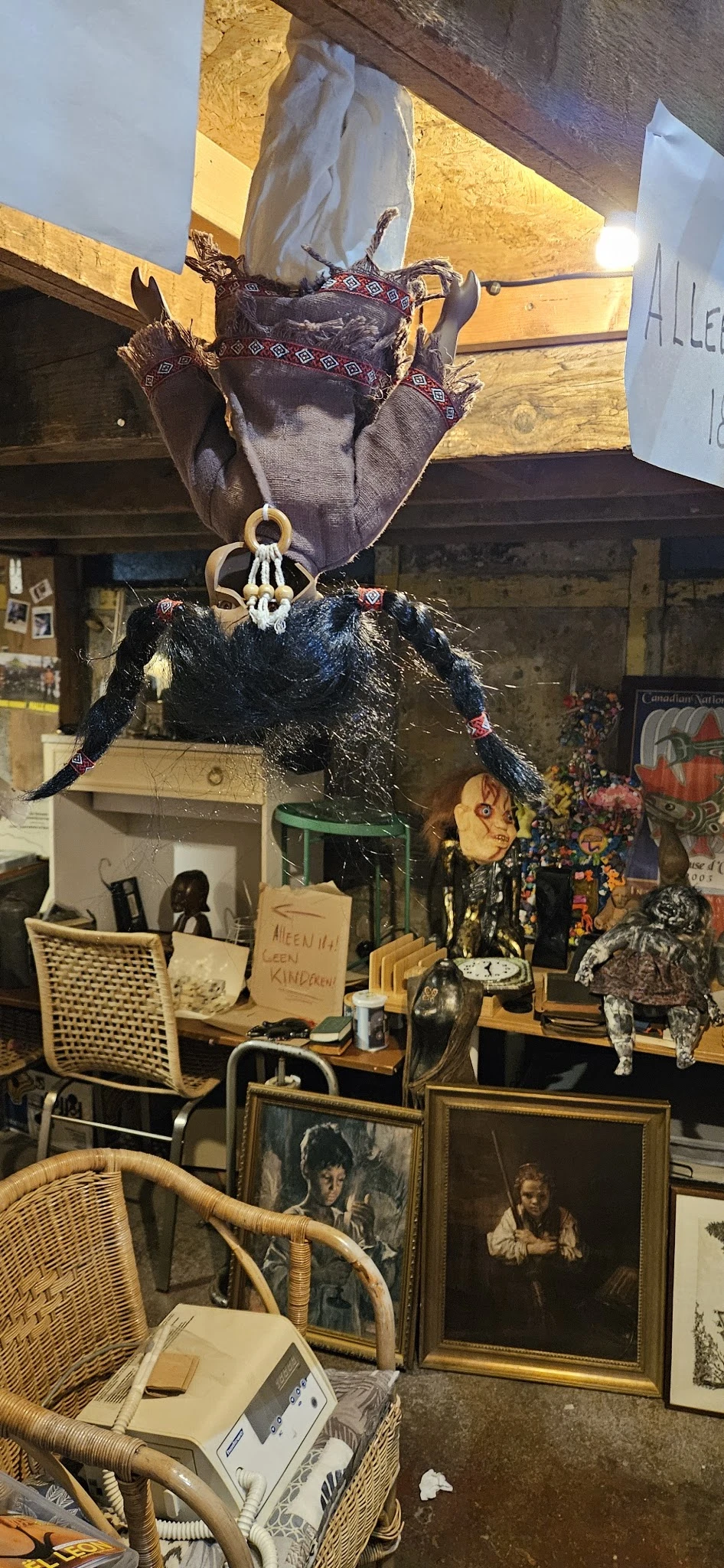 Kringloopwinkelinterieur met uitgestalde spullen, decoraties en een zwarte pluche pop onder een houten kroon.