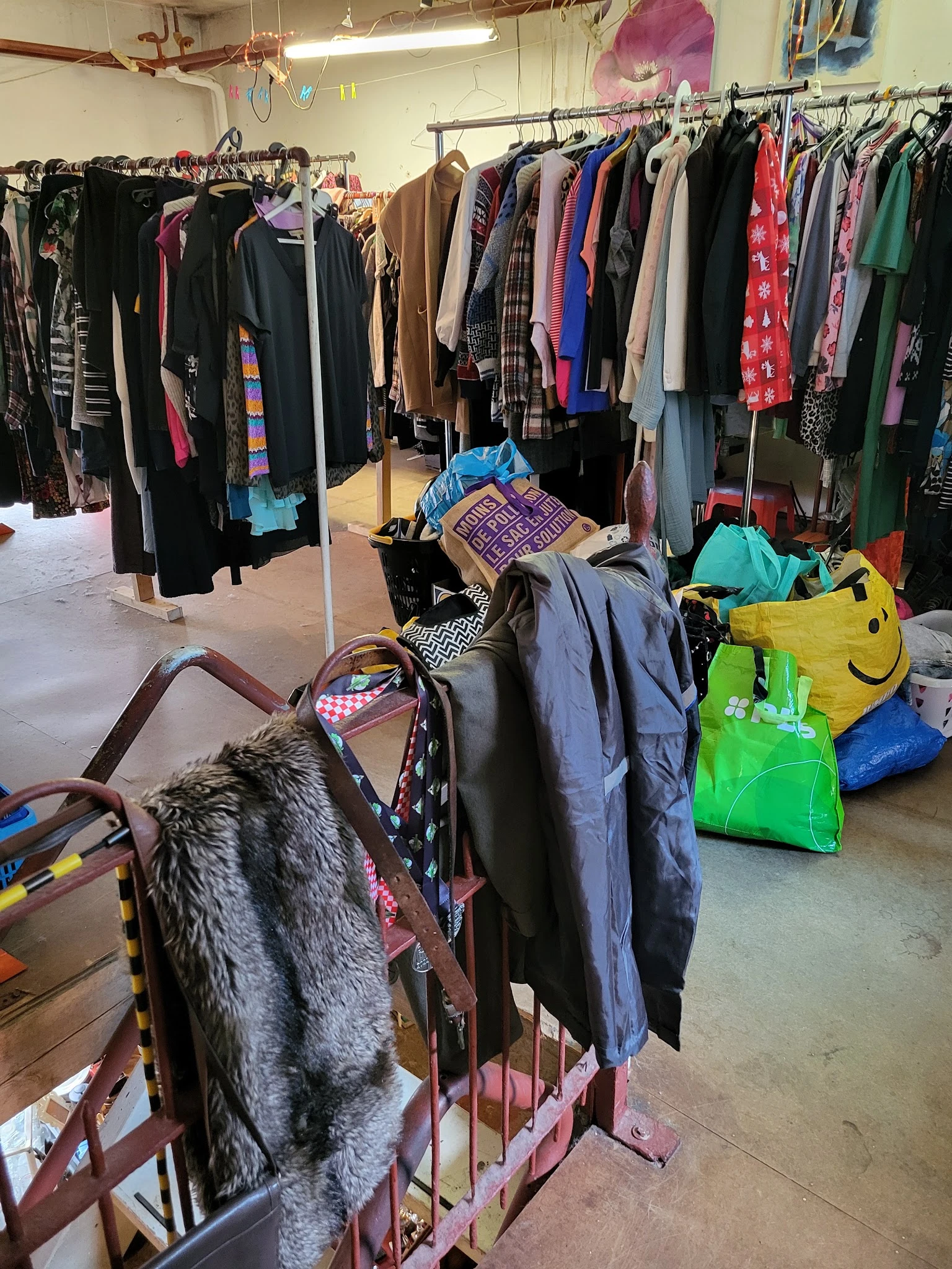 Tweedehands kleding op hangers en in tassen op de winkelvloer