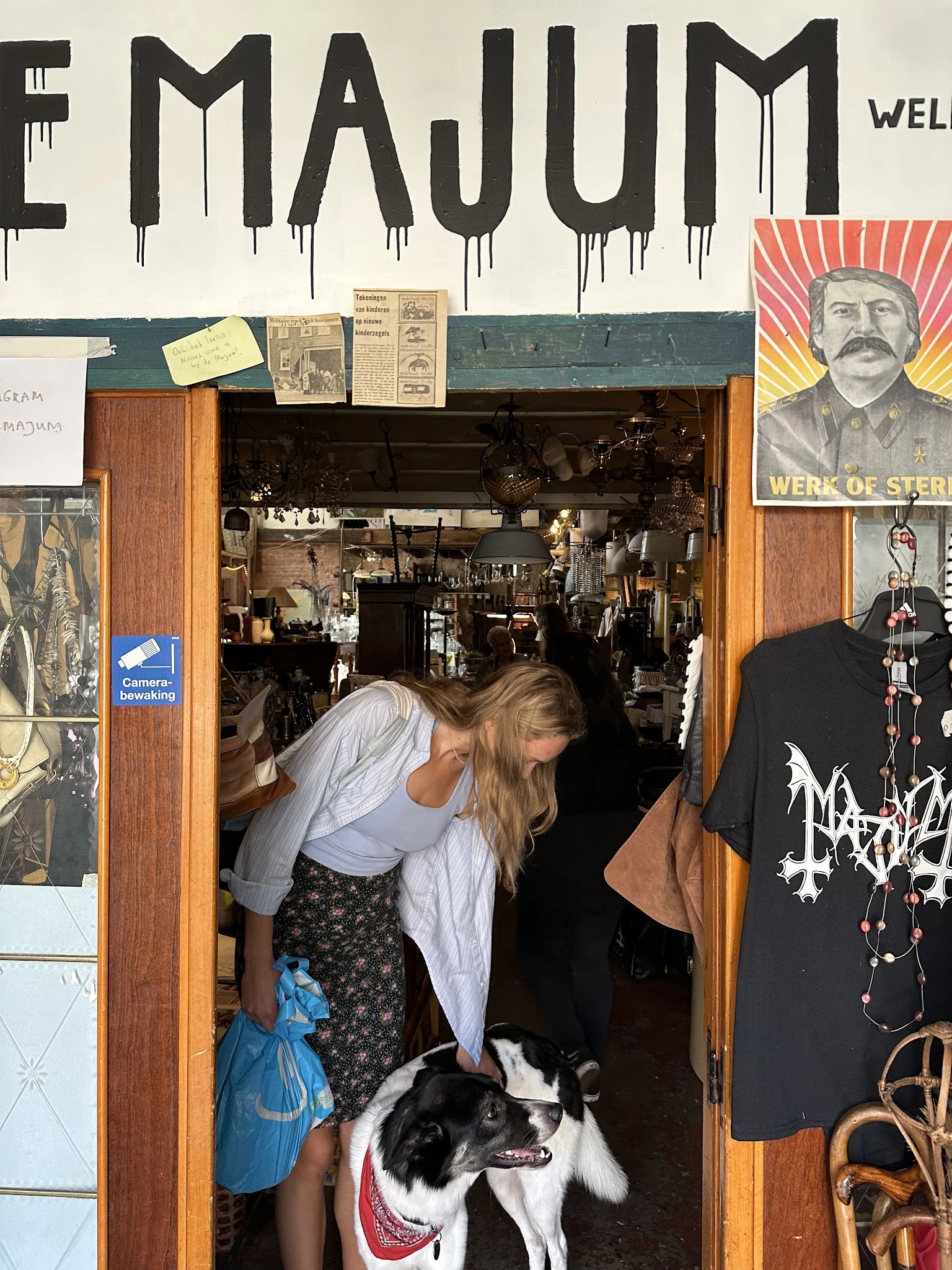 Bezoekers in de ingang van een kringloopwinkel met zicht op het interieur met stellingen en spullen