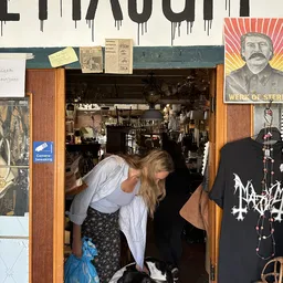 Bezoekers in de ingang van een kringloopwinkel met zicht op het interieur met stellingen en spullen